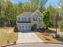 Charming two-story brick home with a well-manicured lawn, lush landscaping, and a three-car garage at 2890 Canter Meadow Dr, Cumming, GA 30040