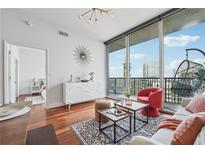 Bright living room with hardwood floors, modern furniture, and floor-to-ceiling windows with balcony access at 1080 Peachtree Ne St # 2416, Atlanta, GA 30309