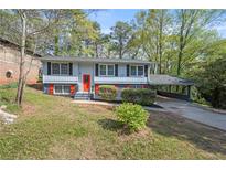 Well-maintained home with a red door, covered parking, and mature landscaping at 2352 S Hairston Rd, Decatur, GA 30035