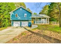 Charming home featuring a two-car garage and covered porch, surrounded by mature trees at 622 Jockey Ln, Auburn, GA 30011