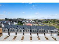New townhomes with brick accents, white garage doors, and landscaping offer modern curb appeal at 11561 Kimberly Way # 23, Hampton, GA 30228