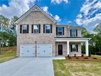 Charming two-story brick home with a two-car garage, landscaped yard, and covered entryway at 679 Egrets Landing Lot 57, Covington, GA 30014