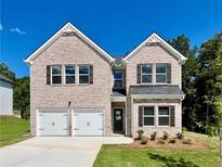 Charming two-story brick home featuring a two-car garage and well-manicured lawn against a bright blue sky at 679 Egrets Landing Lot 57, Covington, GA 30014