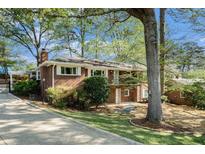 Charming brick home with a well-manicured lawn, mature trees, and a convenient carport, blending classic appeal with modern comfort at 2210 Leafmore Dr, Decatur, GA 30033