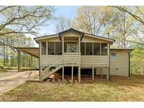 Inviting exterior showcasing a charming tan home with a screened-in porch and convenient carport at 5026 Daniel Mill Rd, Winston, GA 30187