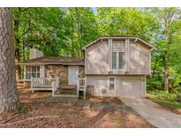 Two-story home featuring stone accents, complemented by a lush, wooded front yard at 5307 Jay Nw Way, Lilburn, GA 30047