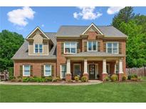Charming brick home with a welcoming front porch and lush green lawn at 1005 Anise Ct, Dacula, GA 30019