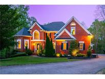 Charming brick home with manicured lawn, mature trees, and an inviting circular driveway at twilight at 4799 Winterview Ln, Douglasville, GA 30135
