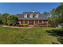 Charming brick home boasts a manicured lawn and lush landscaping with a covered front porch and dormer windows at 200 Sugar Mill Ln, Canton, GA 30115