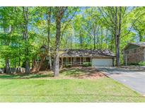 Charming one story brick home featuring a two car garage, covered front porch, and mature trees at 2352 Rockwood Way, Stone Mountain, GA 30087