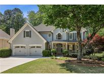 Charming two-story home with a well-manicured lawn, covered porch, and attached two-car garage at 12370 Preserve Ln, Johns Creek, GA 30005