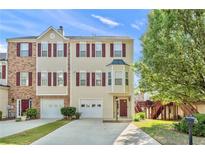 Inviting townhome with red shutters, a two car garage, and well-maintained landscaping at 745 Abbotts Mill Ct, Johns Creek, GA 30097