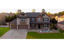 Beautiful two-story home featuring a well-manicured lawn, stone accents, and a two-car garage at 552 Warrenton Run Dr, Sugar Hill, GA 30518