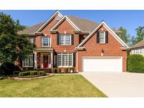 Stately two-story brick home featuring a well-manicured lawn, attached garage and a classic red front door at 2553 Twilight Vw, Snellville, GA 30078