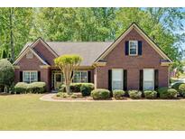 Charming brick home with manicured lawn, complemented by mature trees and classic black shutters at 4309 Milford Pl, Hoschton, GA 30548