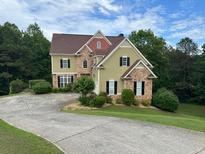 Charming two-story home with a long driveway and well-manicured lawn surrounded by lush trees at 5737 Russell Ct, Douglasville, GA 30135