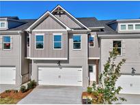 Charming townhome features a two-car garage, brick accents, and a well-maintained front yard, under a clear blue sky at 1237 Fern Ridge Ct # 18, Norcross, GA 30093