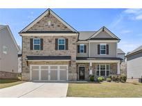 Charming two-story home with a stone and siding exterior, a well-manicured lawn, and a two-car garage at 1602 Dover Creek Ln, Lawrenceville, GA 30045