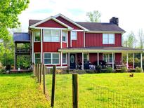Charming two-story home features a covered porch, second-story deck, large windows, and a spacious lawn with fencing at 68 Riveree Rd, Brooks, GA 30205