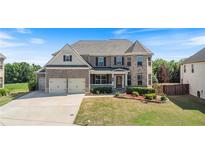 Beautiful two-story brick home with a well-manicured lawn, three-car garage and covered front porch at 4250 Harrison Lndg, Cumming, GA 30041