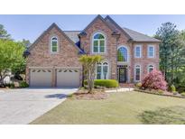 Charming two-story brick home featuring a well-manicured lawn, dual garage, and elegant arched windows at 1315 Chattahoochee Run Dr, Suwanee, GA 30024