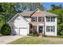 Charming two-story home with a brick facade, black shutters, and a well-maintained front yard at 5108 Staplehurst Ln, Woodstock, GA 30189