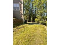 An expansive backyard with mature trees and an overgrown lawn at 7027 Grinder Drive, Austell, GA 30168