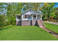 Charming home features a stone foundation, neutral siding and inviting front porch, nestled among mature trees at 1685 Carroll Nw Dr, Atlanta, GA 30318