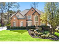 Charming brick home featuring a lush green lawn and manicured landscaping at 317 Vista Lake Dr, Suwanee, GA 30024