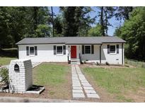 Charming ranch home featuring a freshly painted exterior, a red front door, and a well-maintained front lawn at 3811 Crosby Nw Dr, Atlanta, GA 30331