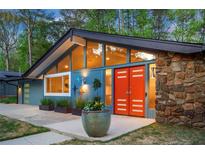 A unique home with a modern design featuring a stone accent wall and vibrant orange double-door entry at 2895 Dunnington Cir, Atlanta, GA 30341