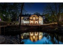 Stunning exterior view of a modern home reflected in a tranquil pond at night at 2750 Interlaken Dr, Marietta, GA 30062