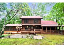 Charming log home with a red metal roof, spacious porch and screened in porch surrounded by mature trees at 800 Knox Ln, Canton, GA 30114