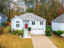 Charming home featuring a red front door, landscaped yard, and attached two-car garage, nestled among mature trees at 760 Whitehall Way, Roswell, GA 30076