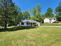 Charming single-story home with a well-maintained lawn and inviting curb appeal on a sunny day at 7235 Hummingbird Ln, Winston, GA 30187