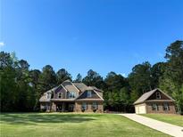 Inviting two-story home with a well-manicured lawn, a matching detached garage, and mature trees at 105 Chantilly Ln, Fayetteville, GA 30215