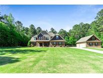 Beautiful two-story brick home with a large front lawn and mature trees at 105 Chantilly Ln, Fayetteville, GA 30215
