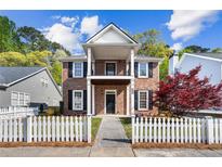 Charming two-story brick home featuring a cozy front porch, black shutters, and a picket fence at 4606 Liberty Square Dr, Acworth, GA 30101
