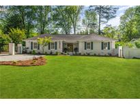 Charming, freshly painted one-story home with a large green lawn and dark blue shutters at 5641 Roberts Dr, Dunwoody, GA 30338