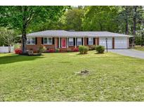 Charming brick home featuring a well-manicured lawn, colorful flowers, and a two-car garage at 241 Burke Cir, Mcdonough, GA 30253