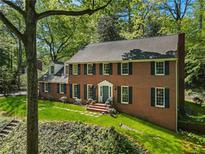 Charming brick home featuring a well-manicured lawn and a beautiful blue entryway, complemented by lush greenery all around at 3380 E Wood Valley Rd, Atlanta, GA 30327