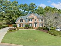 Brick two-story home with manicured lawn, mature trees, and a long driveway in a desirable neighborhood at 374 Meadowmeade Cv, Lawrenceville, GA 30043