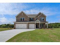 Beautiful two-story brick home with a three-car garage and well-manicured lawn on a sunny day at 119 Felicity Pike, Locust Grove, GA 30248