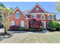 Beautiful brick home with landscaped front yard, vibrant shrubs, and classic architectural details at 870 Longstone Lndg, Alpharetta, GA 30022