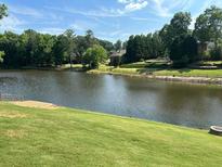 Scenic view of a serene pond surrounded by lush greenery, complemented by a manicured lawn at 870 Longstone Lndg, Alpharetta, GA 30022
