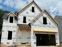 Unfinished two-story house with visible framework showcasing future residence with a 2-car garage and covered front entrance at 3350 Hillshire Dr, Cumming, GA 30028