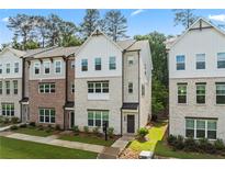 Attractive townhome exterior showcases brick and siding details, complemented by manicured landscaping at 3409 Catalan Aly, Decatur, GA 30032