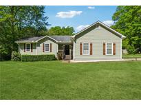 Charming single-story home featuring a well-manicured lawn, decorative shutters, and mature trees offering curb appeal at 705 Trickum Valley Dr, Woodstock, GA 30188