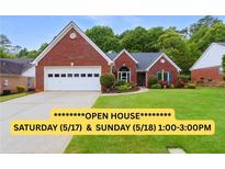 Charming brick home featuring a well-manicured lawn and an attached two-car garage at 1031 Ludwick Way, Lawrenceville, GA 30046