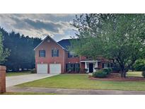 Charming two-story brick home with well-manicured lawn, two-car garage, and mature trees at 1206 Kern Cv, Mcdonough, GA 30253